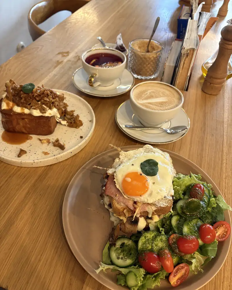Polish breakfast with a fried egg, salad and coffee on a wooden table